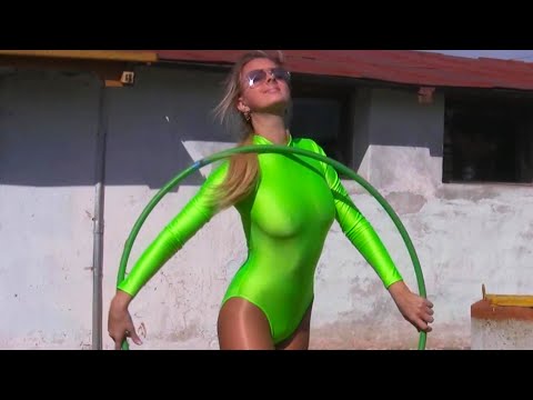 Cool Beautiful Girl Gymnast in a bright tight-fitting shiny spandex lycra suit dances with a hoop